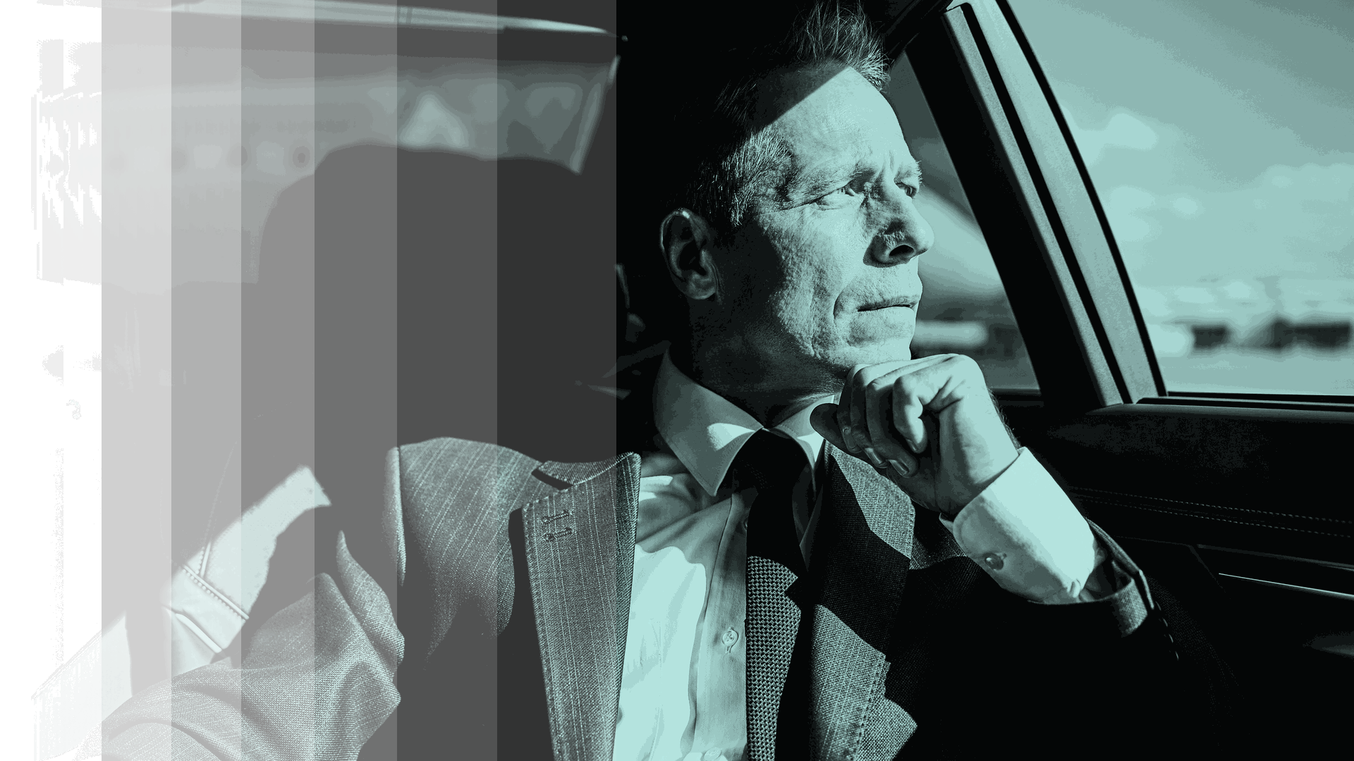Business leader in a suit looking out a car window, deep in thought